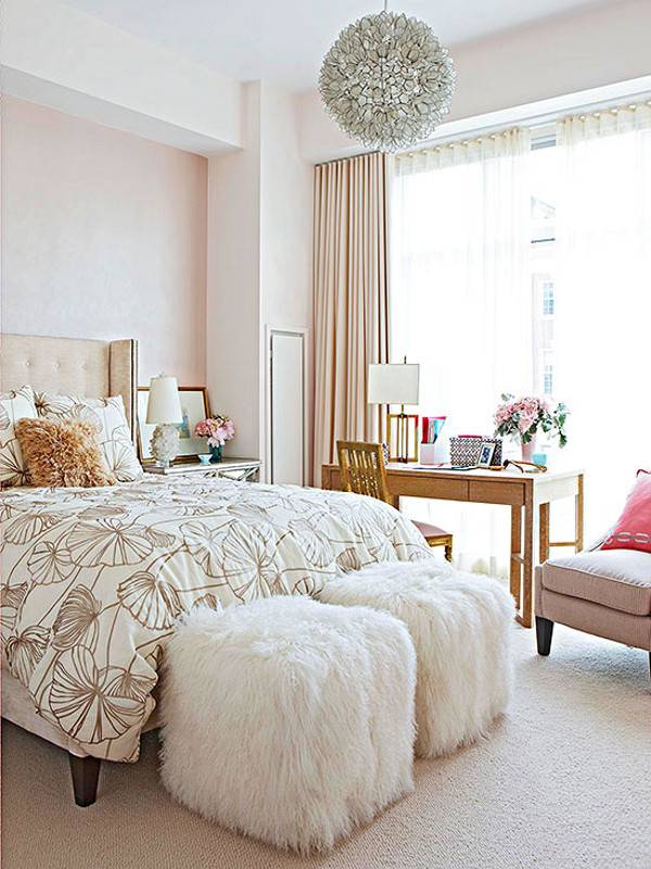Pink color bedroom with bed, fur stools, couch, wooden table with lamp and hanging light to the ceiling.