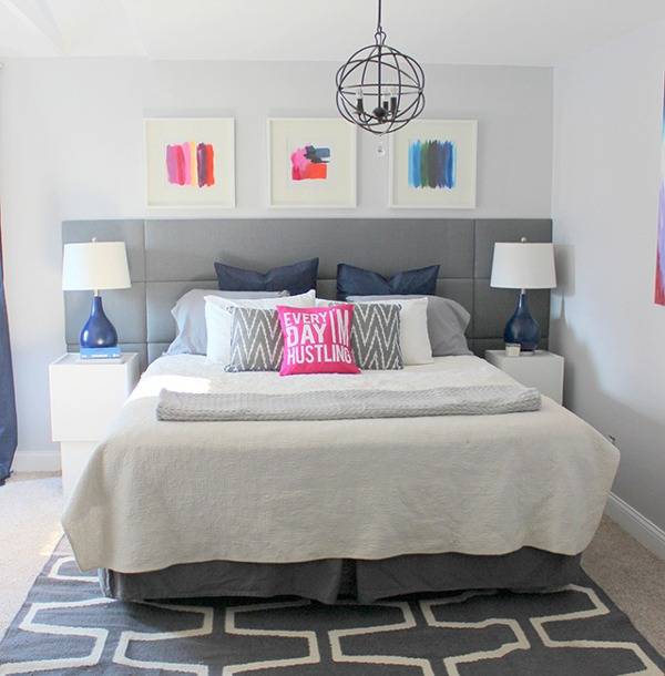 A bed sits on a grey and white rug in a white room.