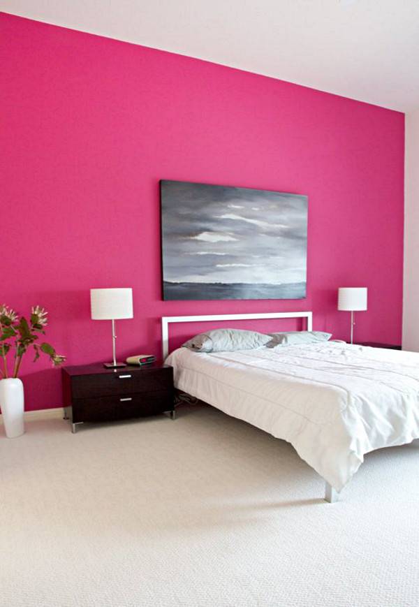 A white bed next to a pink wall.