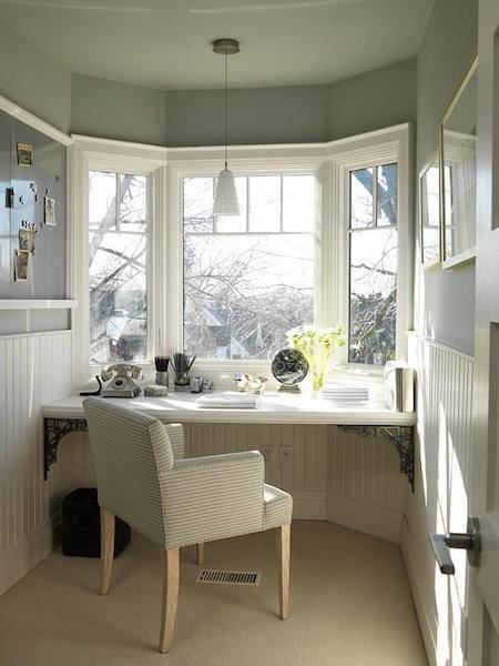 A table sits at the windowed area of a room with a chair.