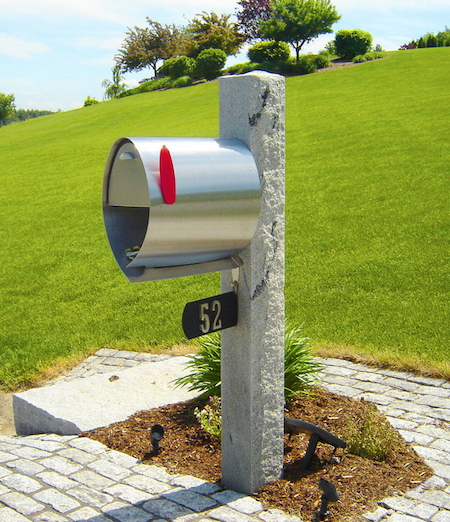A mailbox with the number 52 sits in a stoned area near the grass.