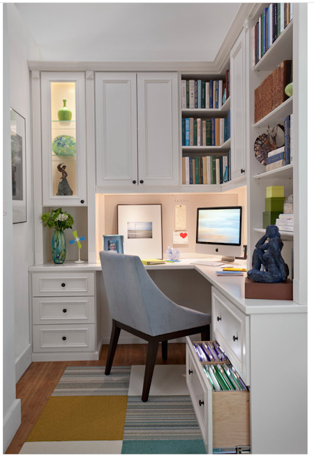 Small home office space with a grey chair facing a computer monitor that is beneath bookshelves.