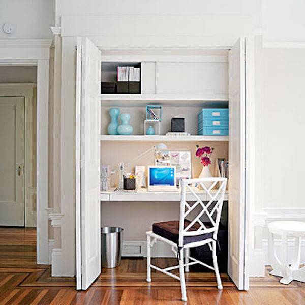Small home office space with wooden shelves built into a closet.