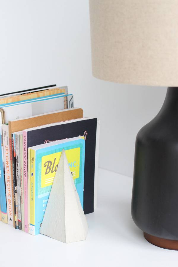Several books sit next to a black a vase.