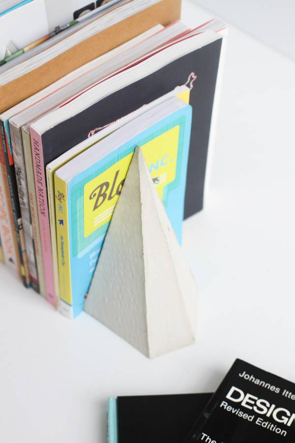 A white pyramid shaped cone holds up some books.