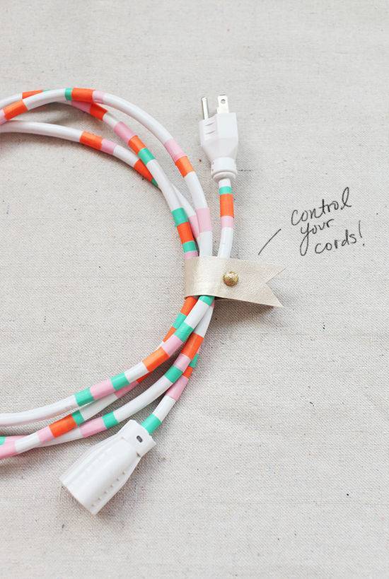 A wrapped up computer cord is covered in orange white and teal crochet yarn.