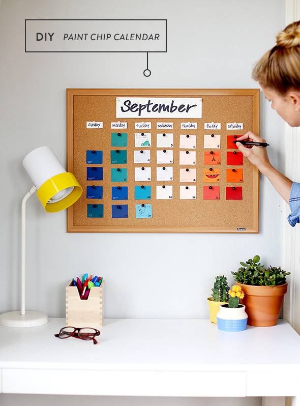 A woman is marking something on a calendar on the wall.