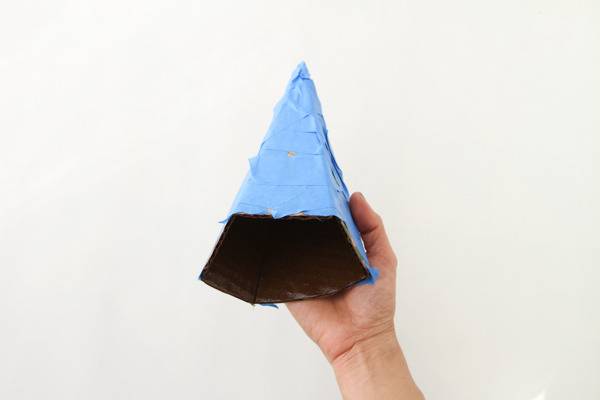 A triangle sculpture that is light blue on the top half and black on the bottom half being held up.