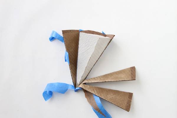 Cardboard shaped into triangular pyramid with cut edges and concrete form within.