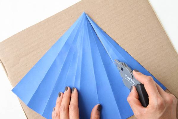 Blue paper being cut on a piece of cardboard.