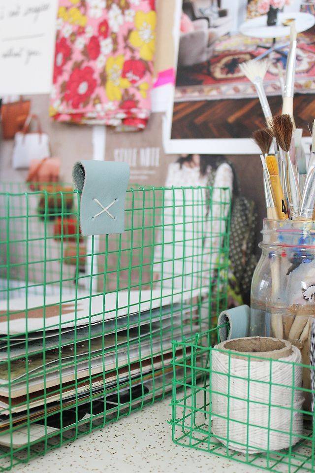 Green basket containing art utensils in an organized way to prevent clutter.