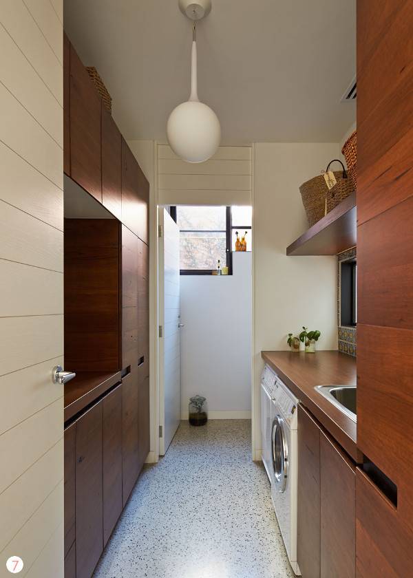 A kitchen with brown cabinets and white wall and floor.