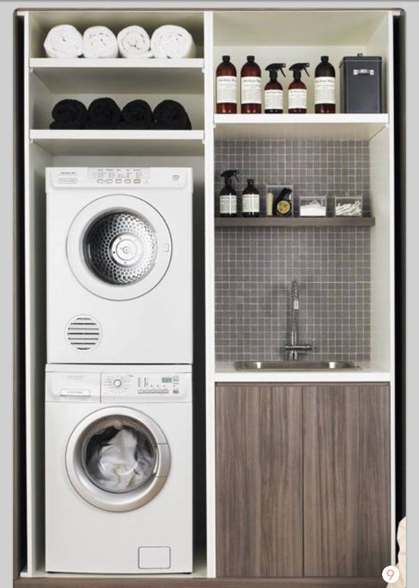 White washer and dryer in a large cabinet that also has bottles and a sink.