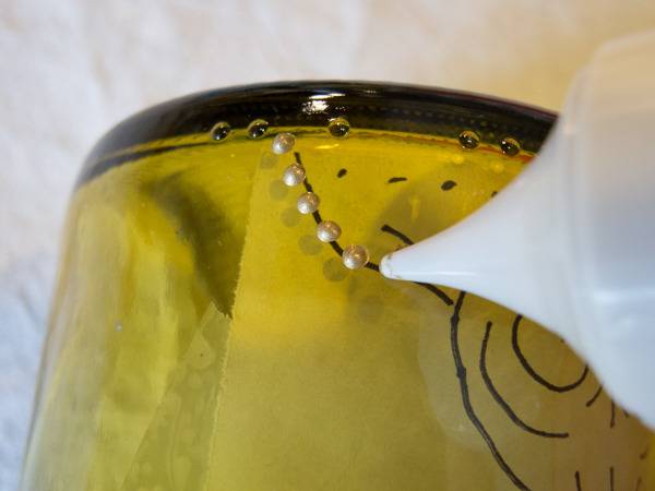 Someone is applying beads onto a yellow and black surface.