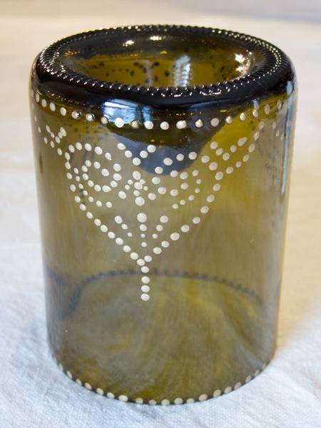 A yellowish colored glass container has cutouts on the sides.