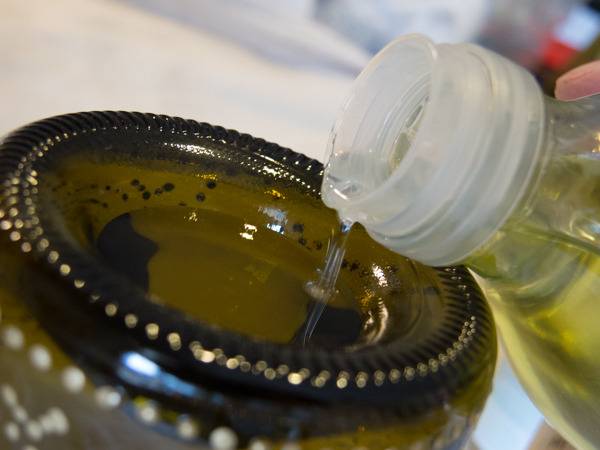 A person slowly pours oil into a decorative container.