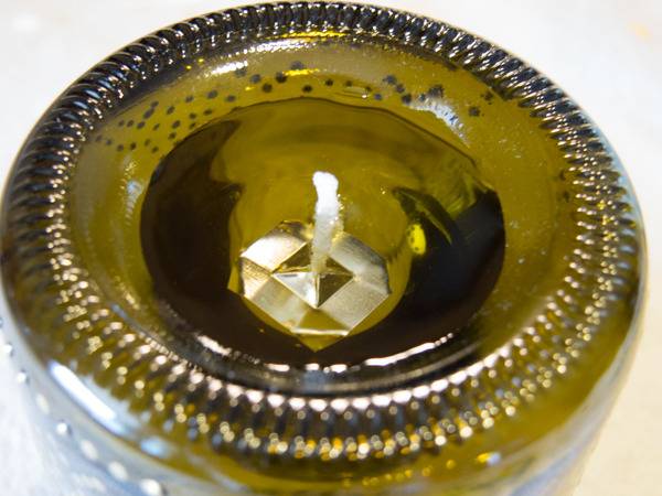 A close up of a gold colored unlit glass candle.