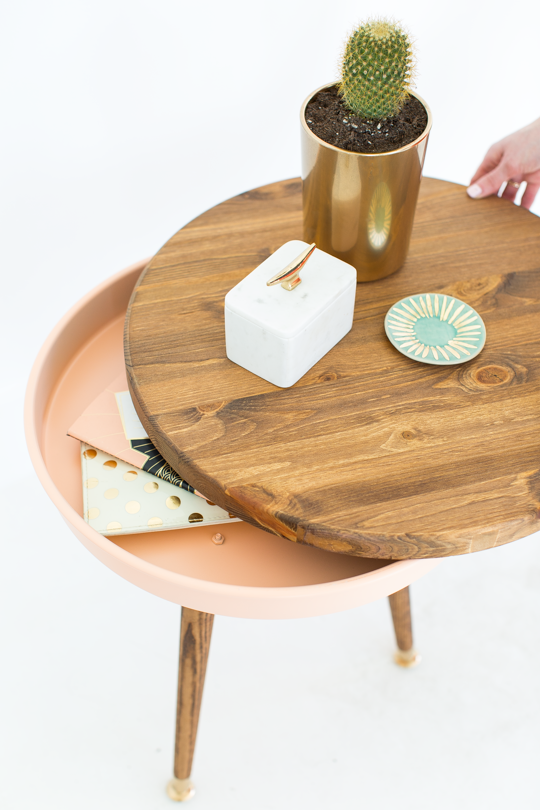 Woman opening wooden storage round table and cactus plant at the top of the table.