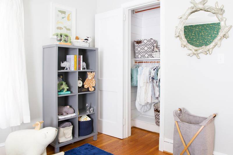 A white room has a gray shelf and hamper.