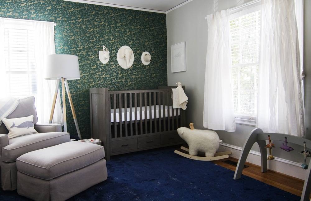 A nursery with a green wall and blue carpet.