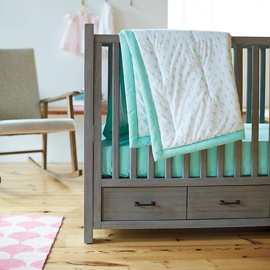 A baby boy's nursery has a wooden crib with green linens.