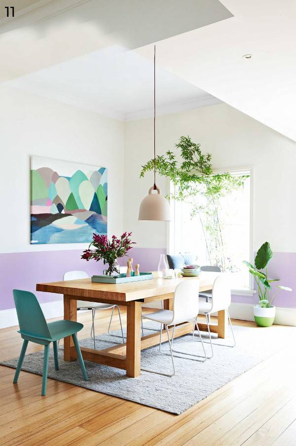 Pastel room with wooden table and chair, potted plants, light and wall art.