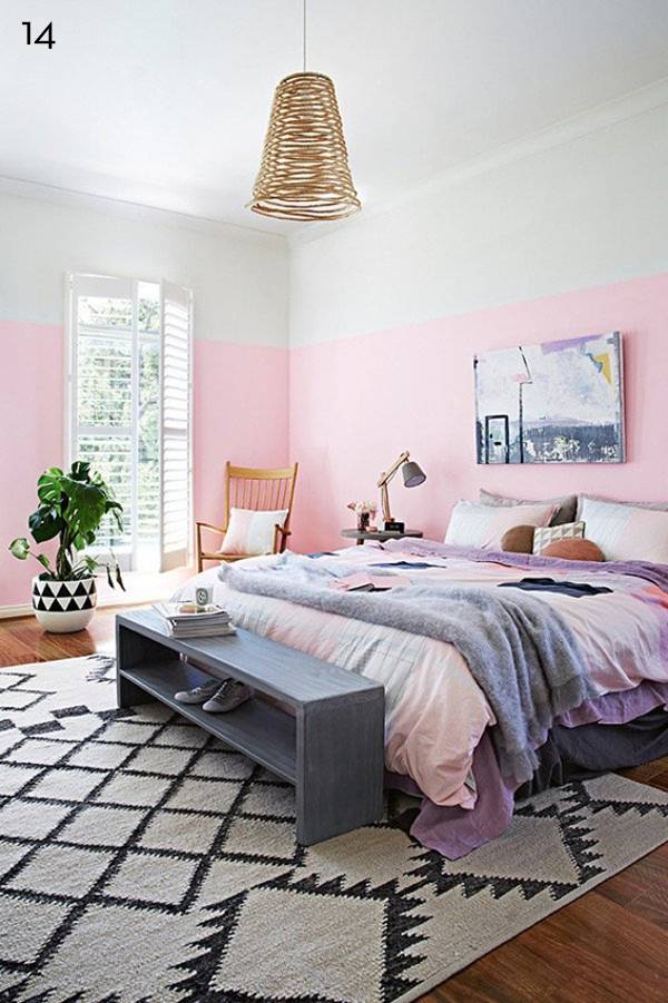 The walls in the bedroom are pink and white, with a huge bed and black and white rug.