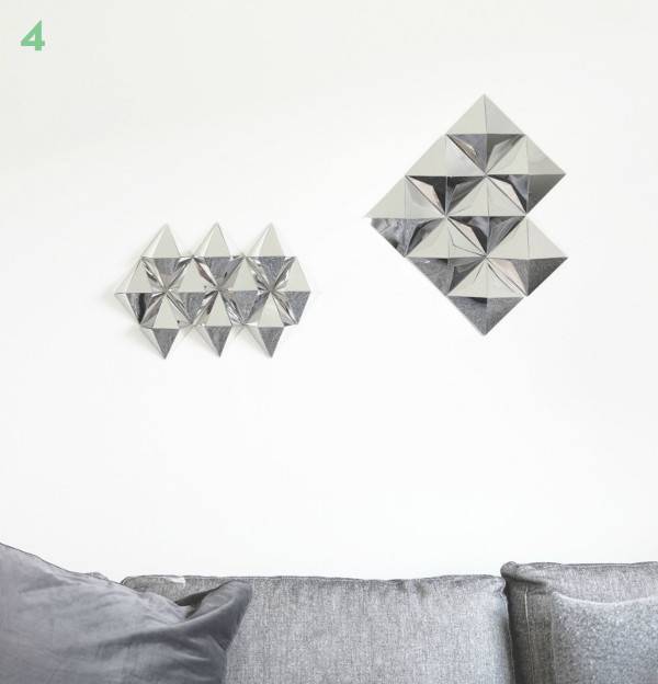 Shiny silver wall ornaments are hanging on the wall behind a grey sofa.