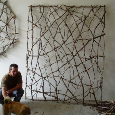 A person is squatting near a dog in a room with nets hanging on the wall.