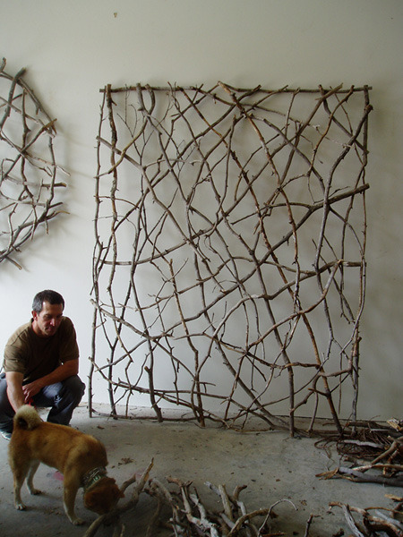 A person is squatting near a dog in a room with nets hanging on the wall.