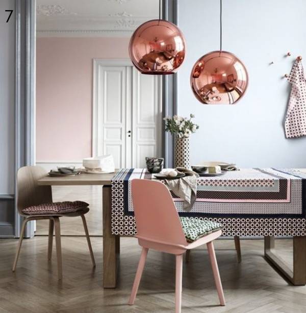 Two rose gold colored balls hang over a dining table.