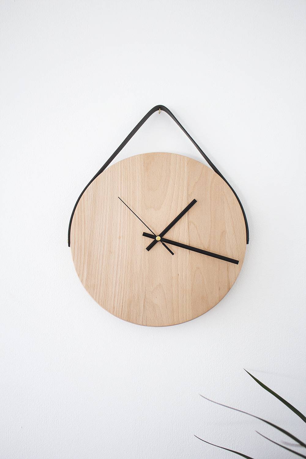 A pink clock hangs from black strings.