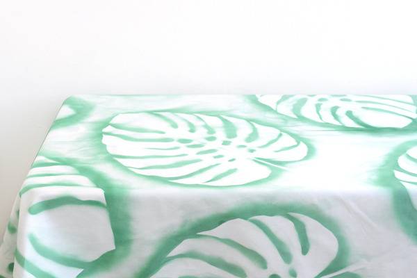 A white table cloth with designs of green leaves.