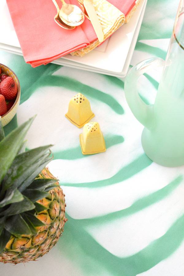 A pineapple and colorful items sit on a green floor.