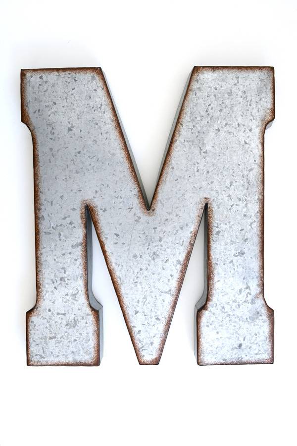 The metal letter M is being displayed with a white background.