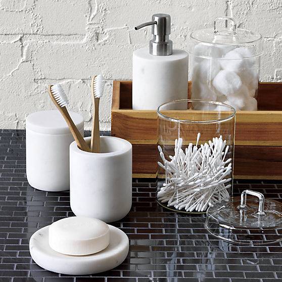 All white bathroom essentials are on a black tile table.