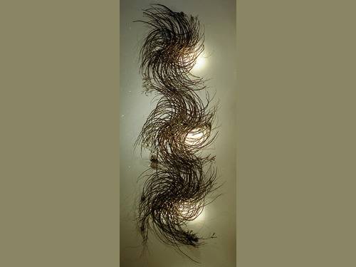 Threads weave around in a vertical arrangement near lights.