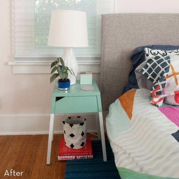 Night stand with table lamp, potted plant at the top and books and bag under the table and bed aside.