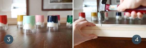 Colored tea candles upside down on a wooden table and hands using a hammer to hammer a nail into wood.