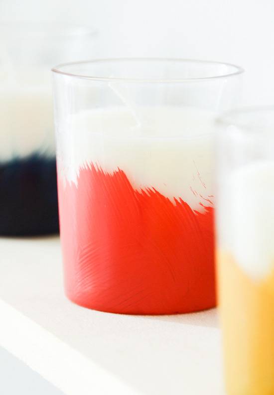 A black, a red, and an orange bottomed candles in clear glass holders.