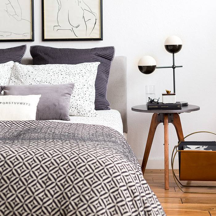 A bedroom has a bed, desk and pictures on the wall.