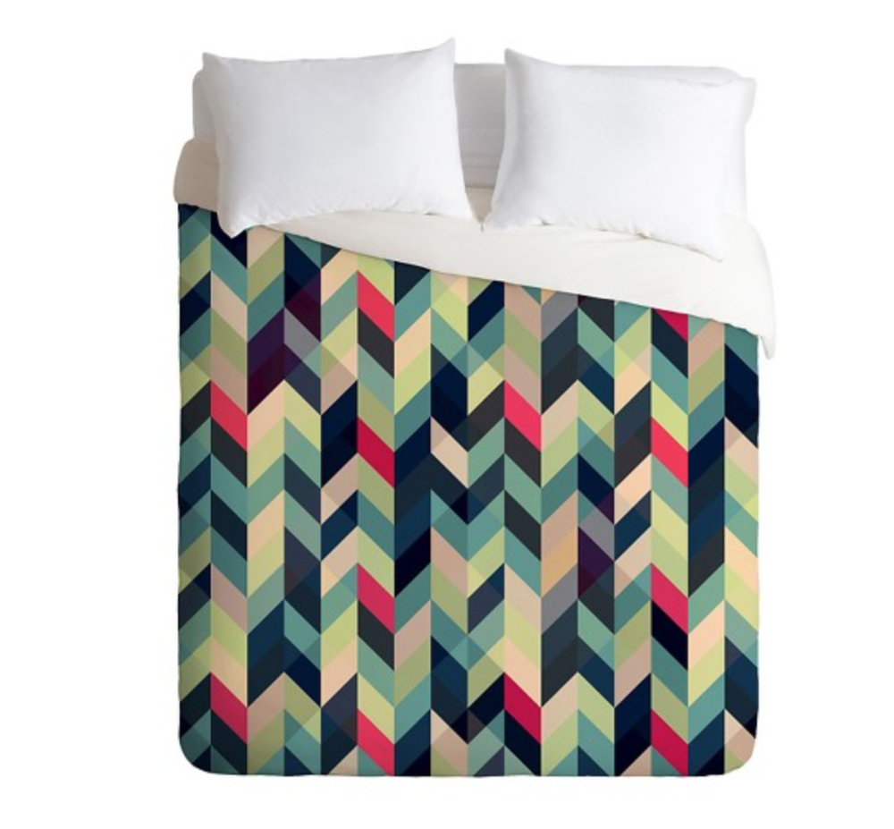 Two white pillows sit at the head of a bed with geometric sheets.