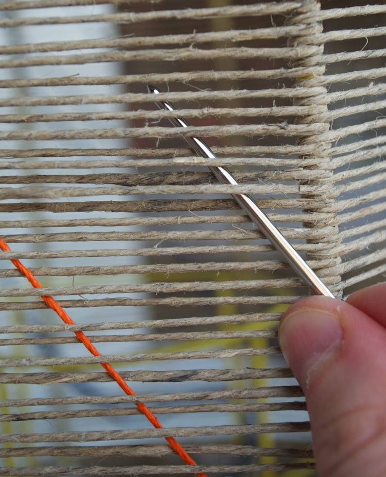 A person is passing two needles through strings.
