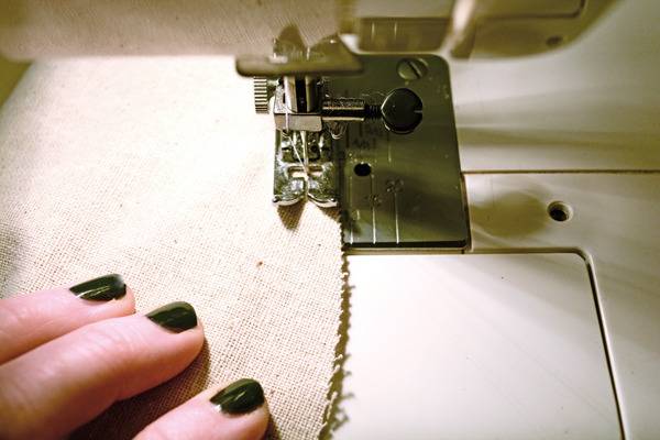A person with black nails is using a sewing machine.