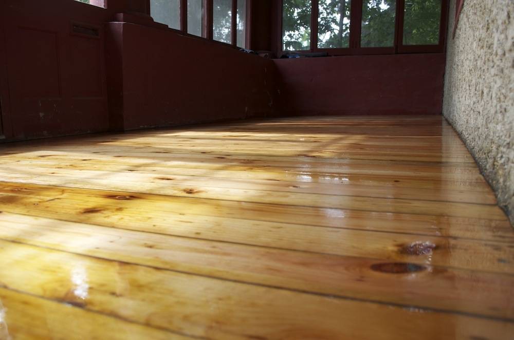 The wooden floor in a room looks sleek and shiny.