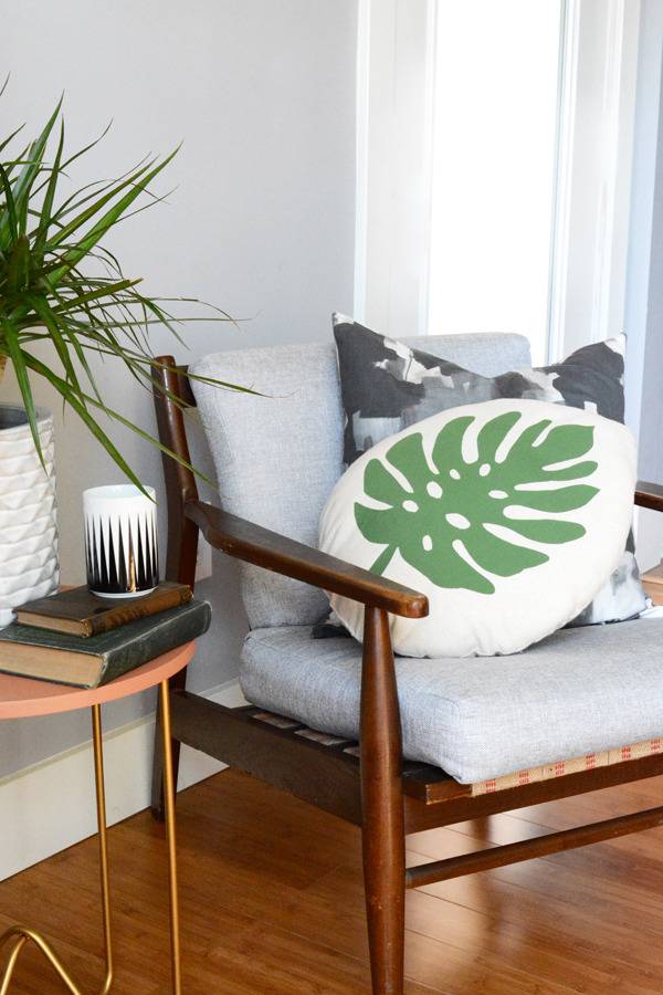 A chair with a large green leaf pillow on it.