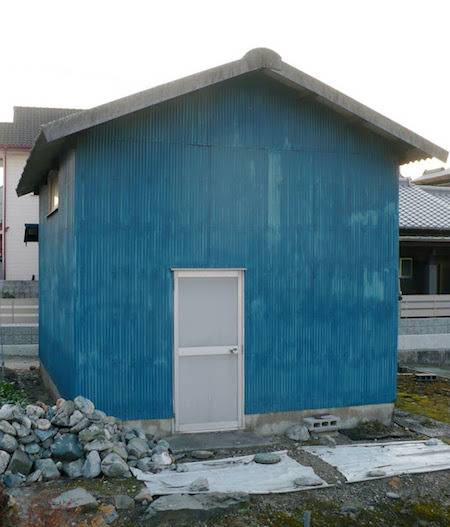 A white door provides entrance into a blue building.