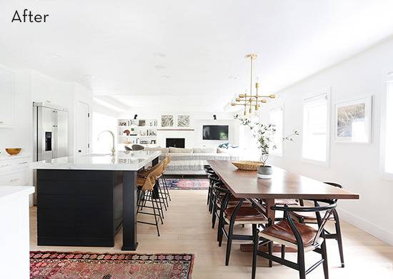 A white kitchen has an island and a large kitchen table.
