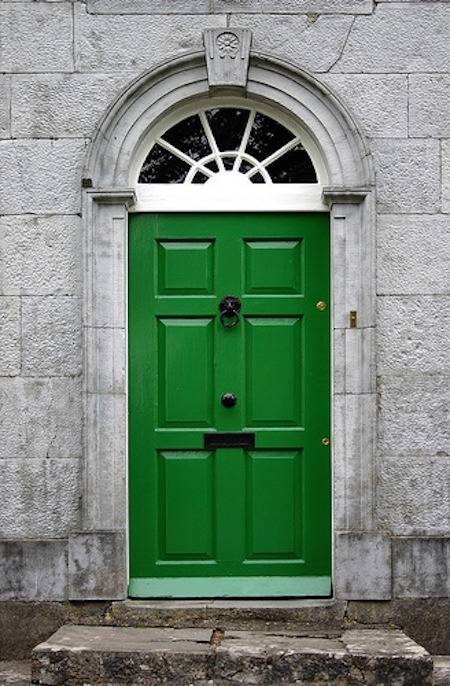 A stone porch has a green front door.