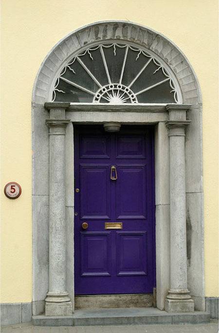 A purple door under a grey archway.